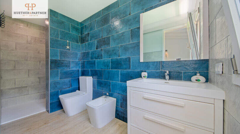 Modernes Badezimmer mit türkisen Wandfliesen, Bidet, WC und weißem Waschtisch im Ferienhaus Sa Ràpita