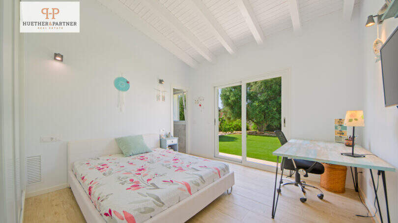 Helles Schlafzimmer mit Holzboden, Balkendecke und Glasschiebetür zum gepflegten Garten – Einfamilienhaus Sa Ràpita