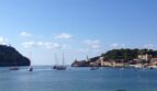 Malerlicher Hafenblick von Port de Sóller mit Segelbooten, Leuchtturm und türkisblauem Mittelmeer auf Mallorca.