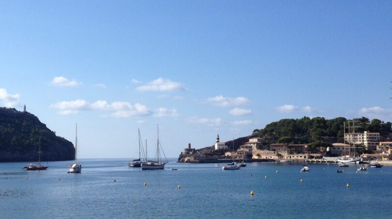 Malerlicher Hafenblick von Port de Sóller mit Segelbooten, Leuchtturm und türkisblauem Mittelmeer auf Mallorca.