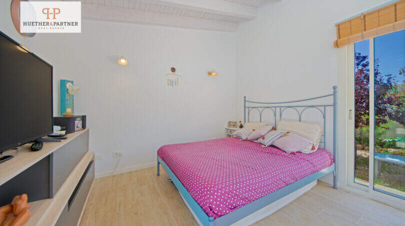 Helles Schlafzimmer mit Doppelbett, Holzboden, TV und Terrassenzugang zum Garten in Sa Ràpita.