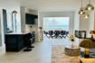Open living-dining area with sea view, dark kitchen island, gold accents and designer lamps in Palma de Mallorca