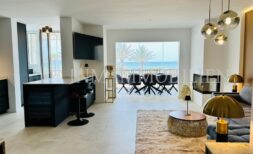 Offener Wohn-Essbereich mit Meerblick, dunkler Kücheninsel, Goldakzenten und Designlampen in Palma de Mallorca