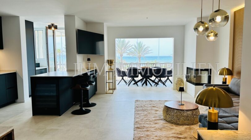 Open living-dining area with sea view, dark kitchen island, gold accents and designer lamps in Palma de Mallorca