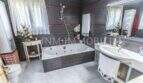Geräumiges Badezimmer der Villa in Marratxí mit Whirlpool-Badewanne, Dusche, Waschbecken und dunklen Fliesen.
