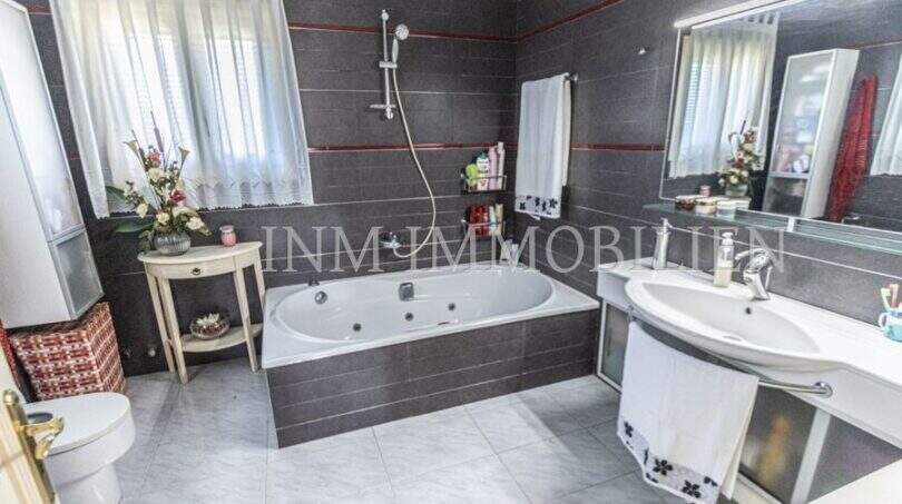 Geräumiges Badezimmer der Villa in Marratxí mit Whirlpool-Badewanne, Dusche, Waschbecken und dunklen Fliesen.