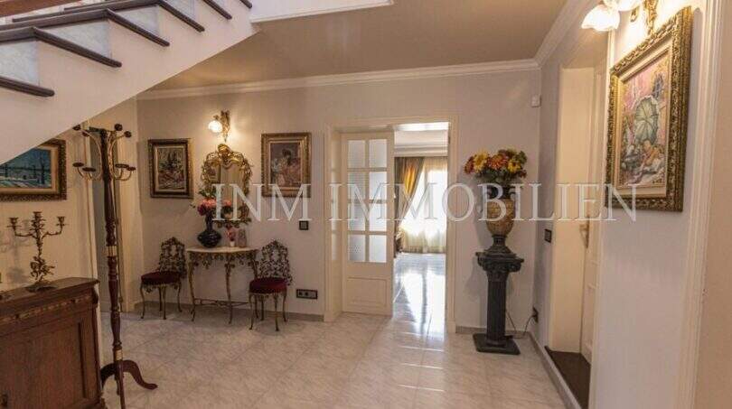 Eleganter Eingangsbereich der Villa in Marratxí mit Treppe, Marmorboden und klassischen Gemälden.