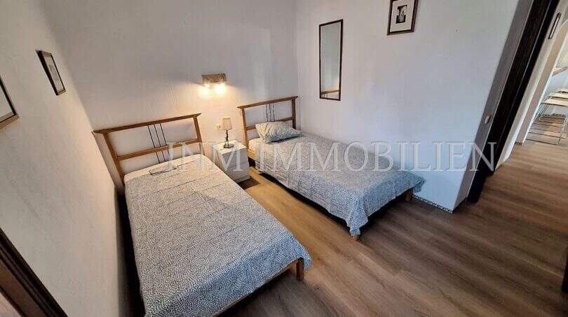 Helles Schlafzimmer mit zwei Einzelbetten, Holzboden und Wandleuchte in Wohnung in Port de Sóller