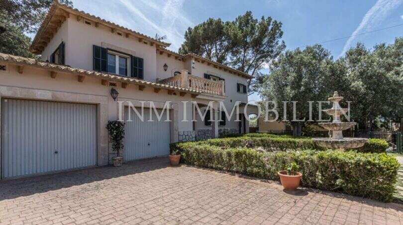 Außenansicht Villa Marratxí: mediterrane Fassade, Doppelgarage, gepflegter Garten mit Springbrunnen und Terrasse.