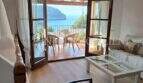Heller Wohnbereich mit Holzboden, weißem Sofa und Terrassenzugang mit Meerblick auf die Bucht von Sóller