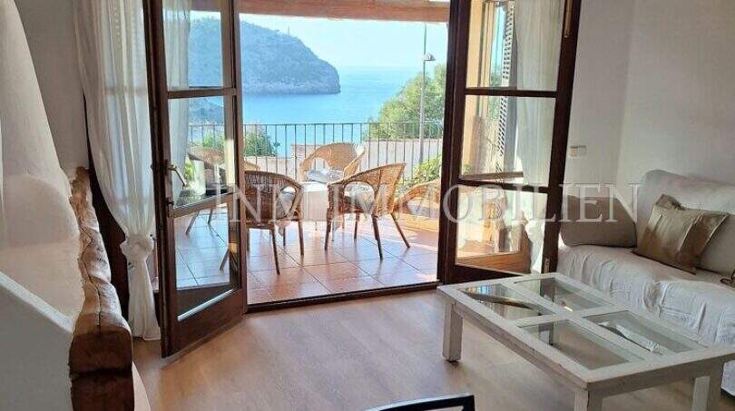 Heller Wohnbereich mit Holzboden, weißem Sofa und Terrassenzugang mit Meerblick auf die Bucht von Sóller