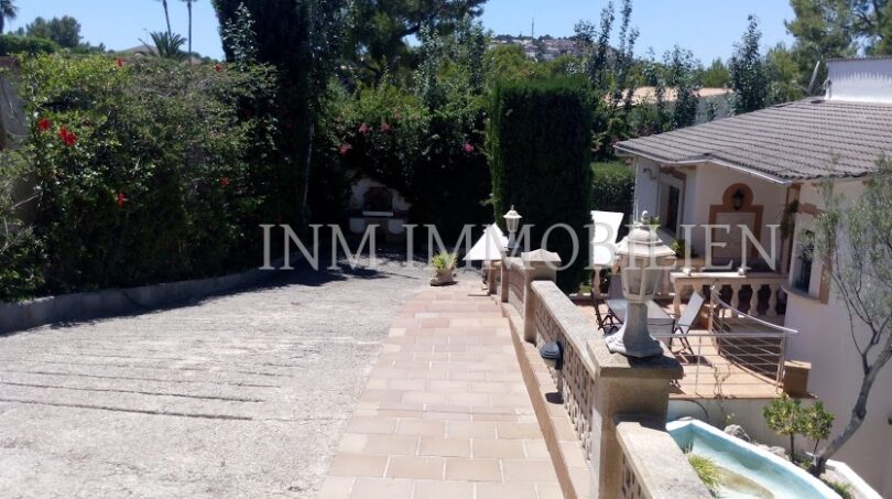 Entrada y terraza de una casa unifamiliar en Santa Ponsa con camino pavimentado y exuberante vegetación