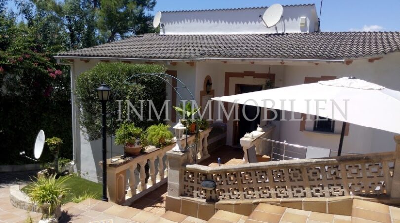 Vista exterior Villa Santa Ponsa: terraza con sombrilla, balaustrada, antenas parabólicas y jardín mediterráneo.