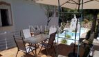 Terraza soleada con muebles de jardín y sombrilla, vista de la piscina y escultura, casa unifamiliar Santa Ponsa