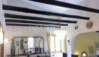 Sala de estar con vigas de madera negra rústicas, techo abovedado y elegante lámpara de araña en villa Santa Ponsa