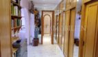 Pasillo luminoso con armarios empotrados de madera, pared de espejo y estantería en casa unifamiliar Santa Ponsa