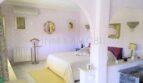 Dormitorio luminoso con cama doble, decoración de pared en púrpura y elegante arco de medio punto en casa unifamiliar Santa Ponsa