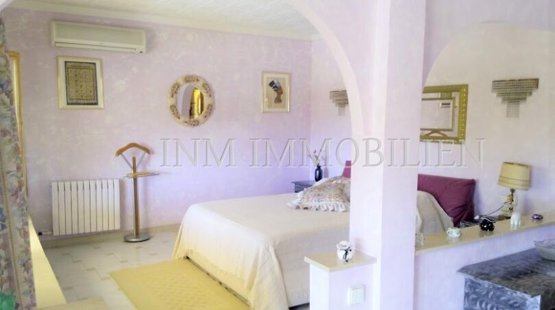 Dormitorio luminoso con cama doble, decoración de pared en púrpura y elegante arco de medio punto en casa unifamiliar Santa Ponsa