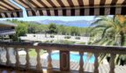 Balcón con toldo, vista de la piscina, palmeras y bahía marina en Santa Ponsa