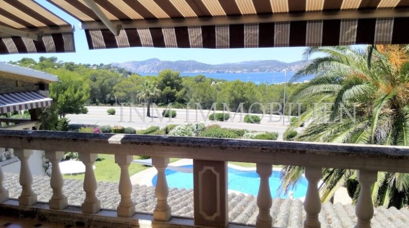 Balcón con toldo, vista de la piscina, palmeras y bahía marina en Santa Ponsa