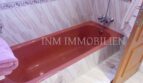 Baño con bañera empotrada roja, baldosas de mármol y puerta de madera en casa unifamiliar Santa Ponsa