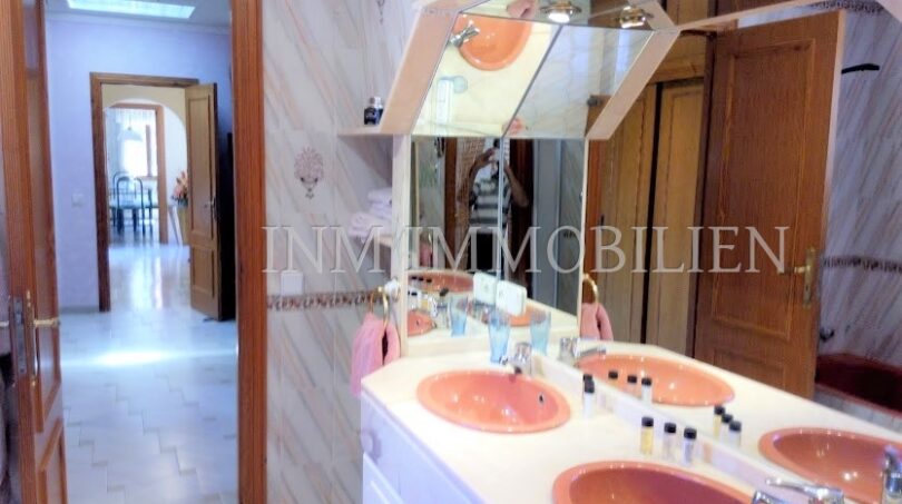 Baño espacioso con lavabo doble en rosa, espejo grande y vista al pasillo de la casa unifamiliar en Santa Ponsa.