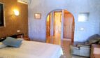 Dormitorio luminoso con cama doble, sillón de cuero, aire acondicionado y elegante paso de arco de medio punto en Santa Ponsa.