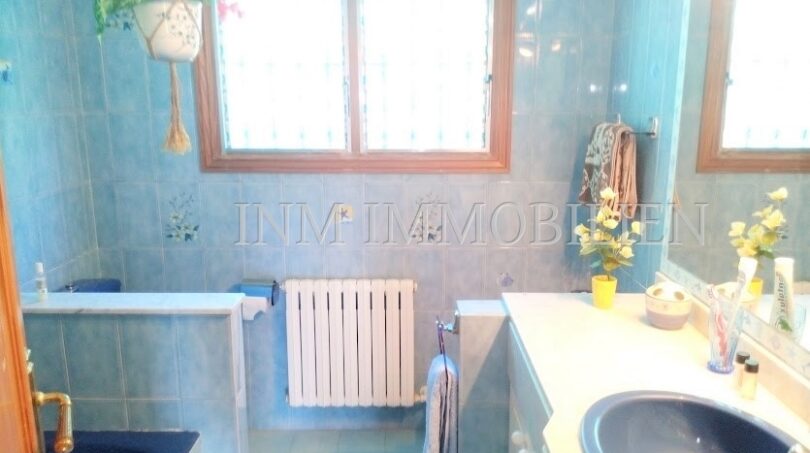 Baño con revestimiento de azulejos azules, radiador, bañera y lavabo azul en casa unifamiliar Santa Ponsa
