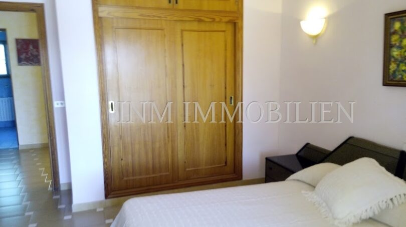 Dormitorio con cama doble, armario empotrado de madera y aplique de pared en casa unifamiliar Santa Ponsa
