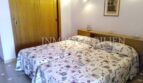 Dormitorio luminoso con cama doble, ropa de cama estampada, armario de madera y lámpara de pared en casa unifamiliar Santa Ponsa