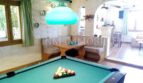 Sala de juegos con mesa de billar, lámpara colgante turquesa y acogedor rincón para sentarse en casa unifamiliar Santa Ponsa