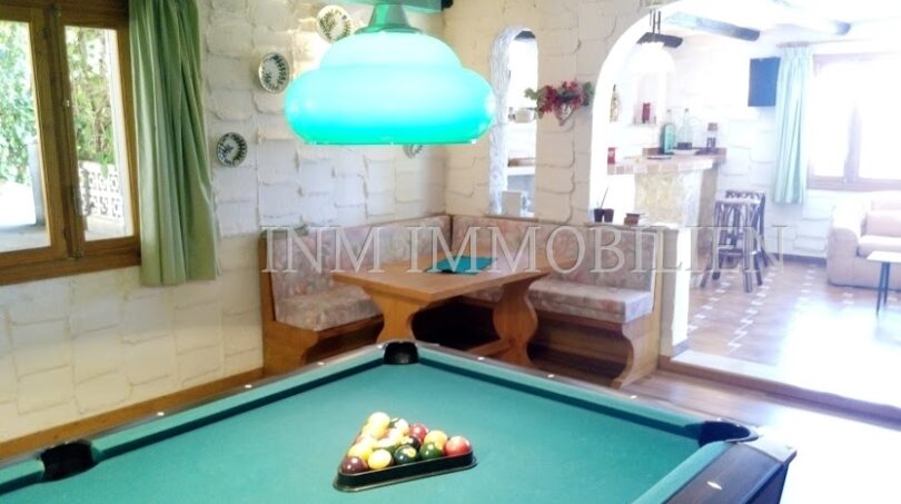 Sala de juegos con mesa de billar, lámpara colgante turquesa y acogedor rincón para sentarse en casa unifamiliar Santa Ponsa