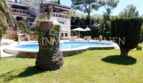 Vista exterior villa Santa Ponsa: Jardín bien cuidado con piscina, palmera y arquitectura mediterránea bajo el sol.