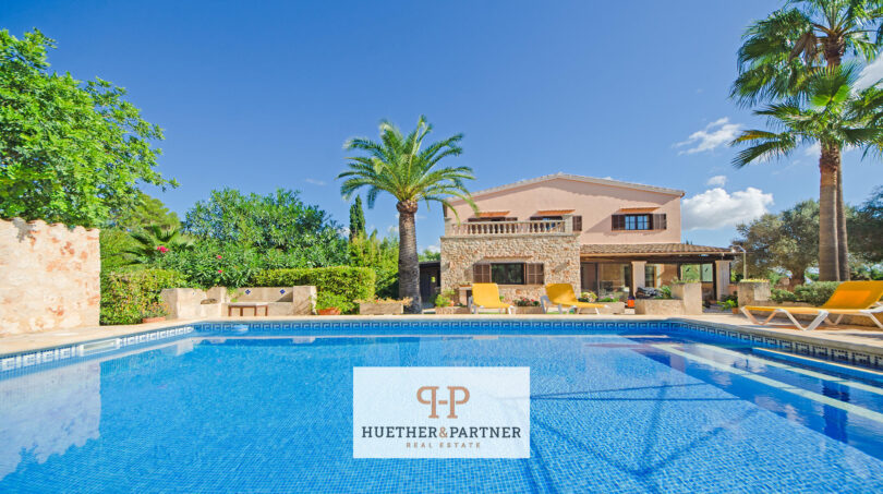 Finca Felanitx: Gran piscina con vistas a casa de campo mediterránea, palmeras y vegetación exuberante