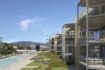 Moderno complejo de nuevos apartamentos en Palmanova con balcones, piscina comunitaria y vistas a la montaña, rodeado de jardines bien cuidados.