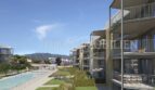 Moderno complejo de nuevos apartamentos en Palmanova con balcones, piscina comunitaria y vistas a la montaña, rodeado de jardines bien cuidados.
