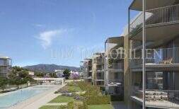 Moderno complejo de nuevos apartamentos en Palmanova con balcones, piscina comunitaria y vistas a la montaña, rodeado de jardines bien cuidados.