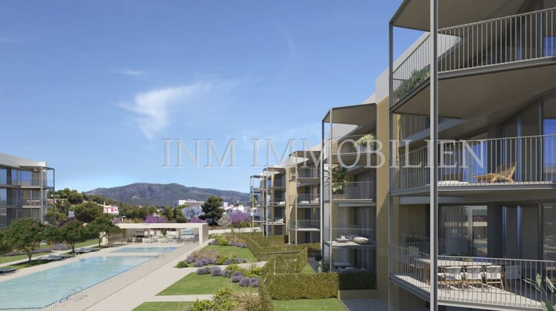 Moderno complejo de nuevos apartamentos en Palmanova con balcones, piscina comunitaria y vistas a la montaña, rodeado de jardines bien cuidados.