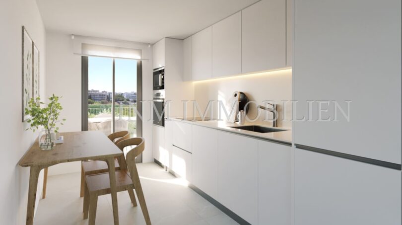 Moderna cocina blanca integrada con mesa de comedor y acceso al balcón en el apartamento áticos de nueva construcción en Palmanova