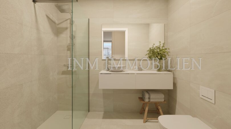 Moderno cuarto de baño del apartamento áticos de nueva construcción en Palmanova con ducha a nivel del suelo, lavabo flotante y azulejos claros.