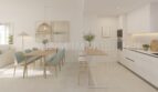 Luminosa zona de estar-comedor con cocina abierta, sillas verde menta y diseño moderno en apartamento áticos de nueva construcción en Palmanova