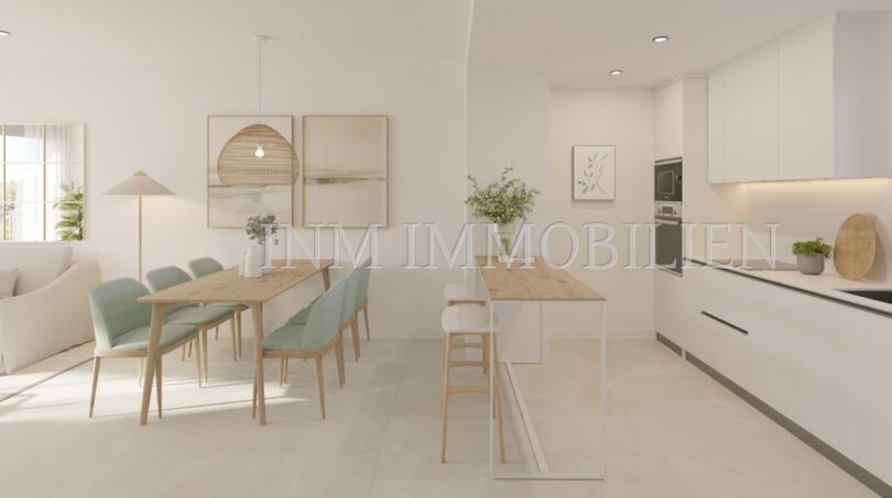 Luminosa zona de estar-comedor con cocina abierta, sillas verde menta y diseño moderno en apartamento áticos de nueva construcción en Palmanova