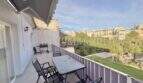 Sonnige Dachterrasse mit Gartenmöbeln, Markise und Blick auf Porto Cristos Altstadt und Grünflächen