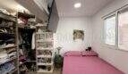 Schlafzimmer mit rosa Bett, TV-Wandhalterung, großem Kleiderbereich und Fenster in Maisonette Porto Cristo