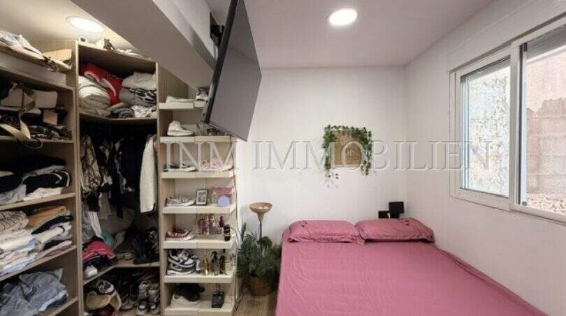 Schlafzimmer mit rosa Bett, TV-Wandhalterung, großem Kleiderbereich und Fenster in Maisonette Porto Cristo
