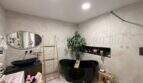 Luxuriöses Badezimmer mit schwarzer Freistehbadewanne, Marmorfliesen und modernem Waschtisch in Maisonette Porto Cristo.