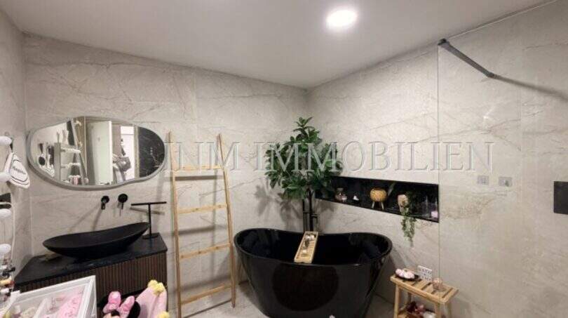 Luxuriöses Badezimmer mit schwarzer Freistehbadewanne, Marmorfliesen und modernem Waschtisch in Maisonette Porto Cristo.