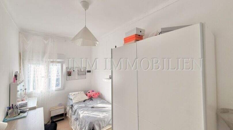 Helles Kinderzimmer mit Einzelbett, weißem Kleiderschrank, Schreibtisch und Fenster in Maisonette-Wohnung Porto Cristo.