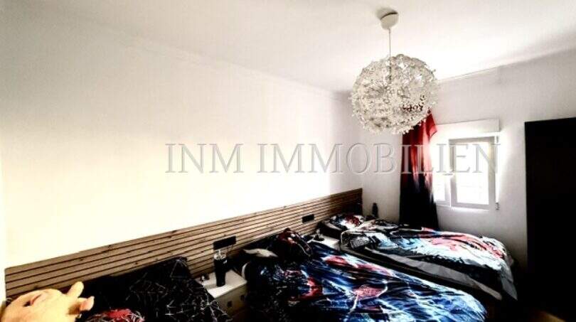 Schlafzimmer der Maisonette in Porto Cristo mit Doppelbett, Holzkopfteil und elegantem Kristalllüster