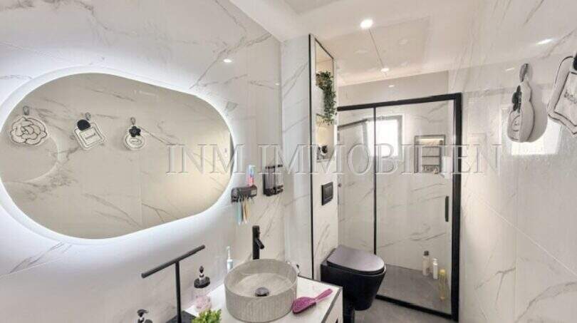 Modernes Badezimmer mit Marmoroptik, Aufsatzwaschbecken, beleuchtetem Spiegel und Glasdusche in Maisonette Porto Cristo